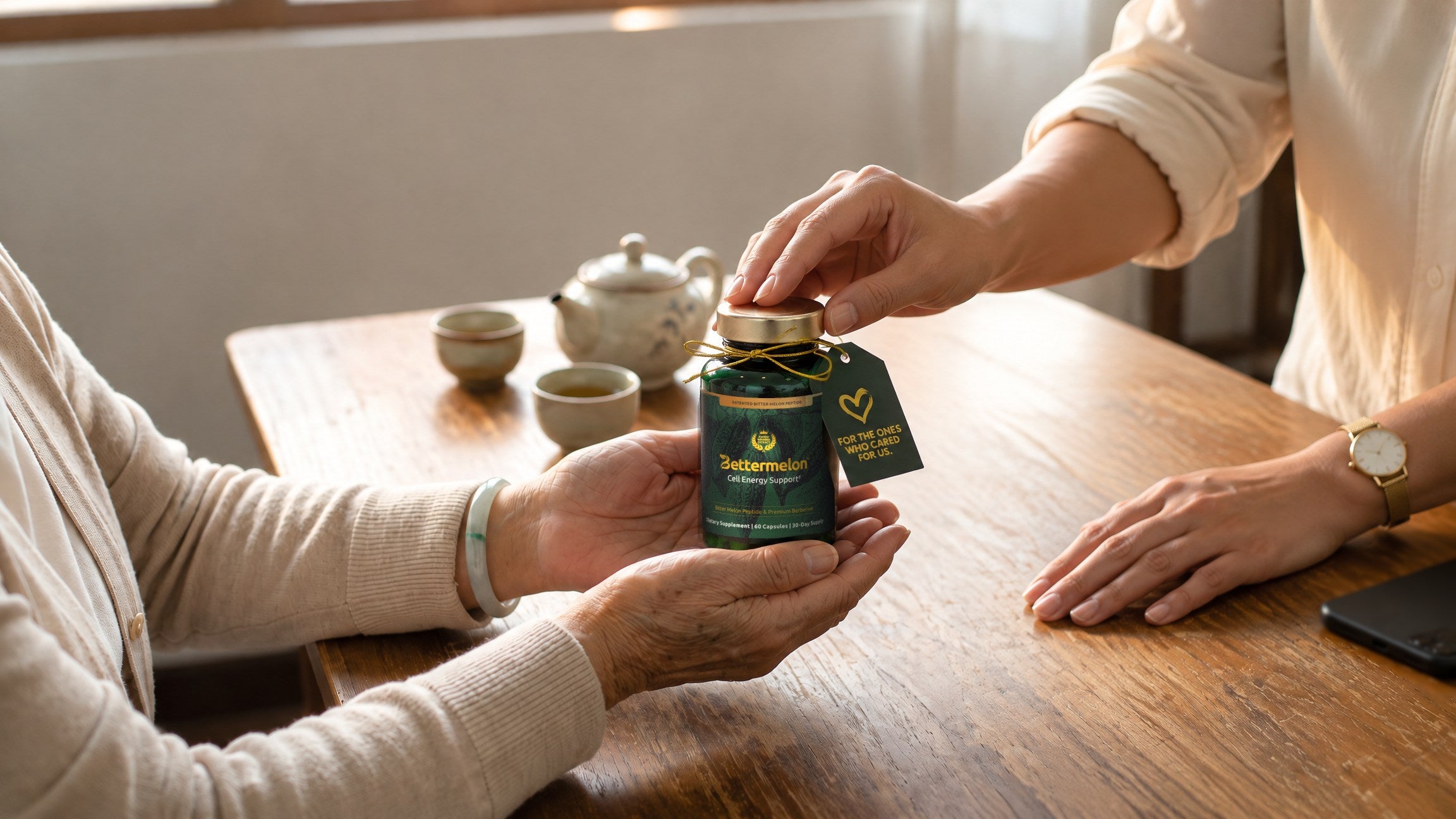 An older woman's cupped hands receive a green Bettermelon bottle with a gift tag from her daughter across a wooden table